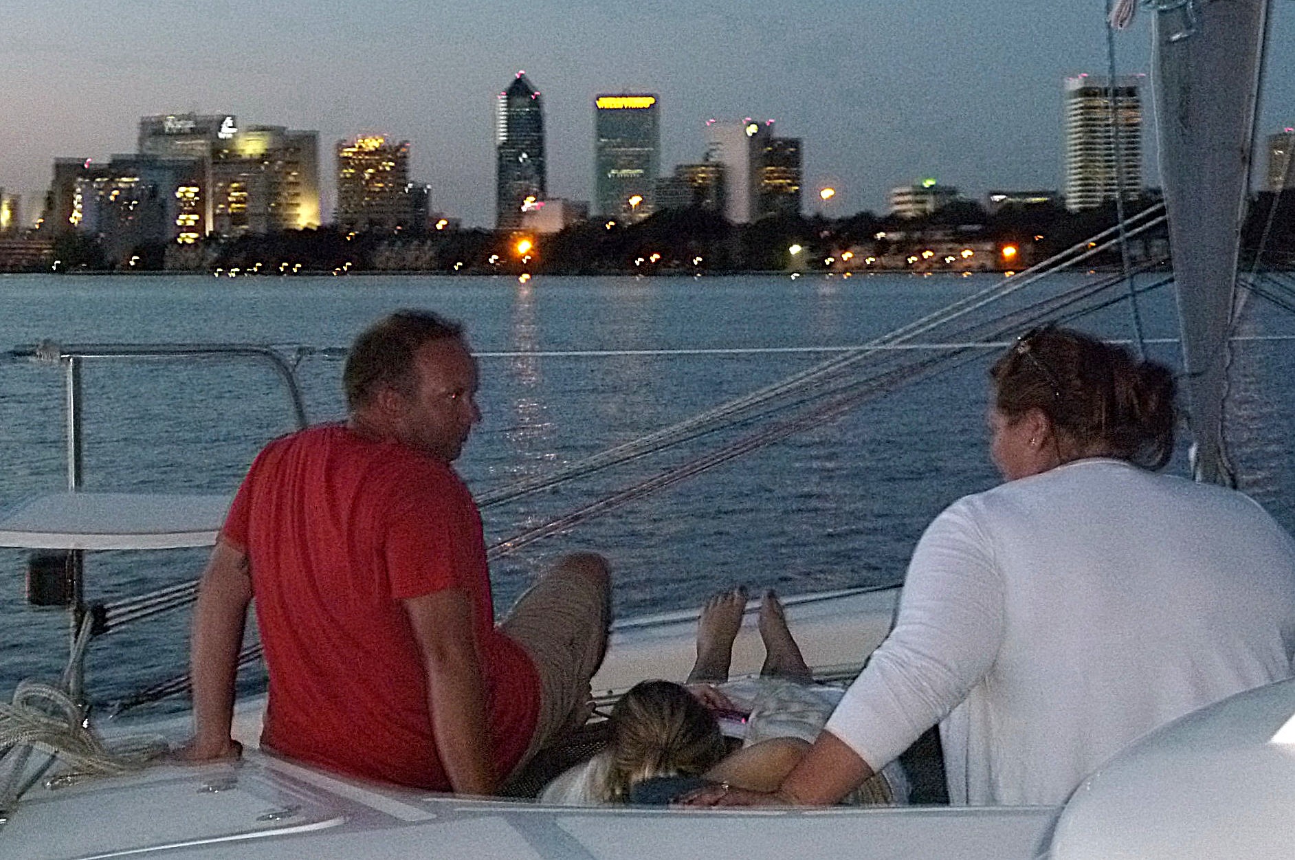 Guests relaxing on deck with the Jacksonville skyline at dusk